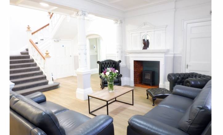 Grand and comfortable entrance hall with feature fireplace and sofas